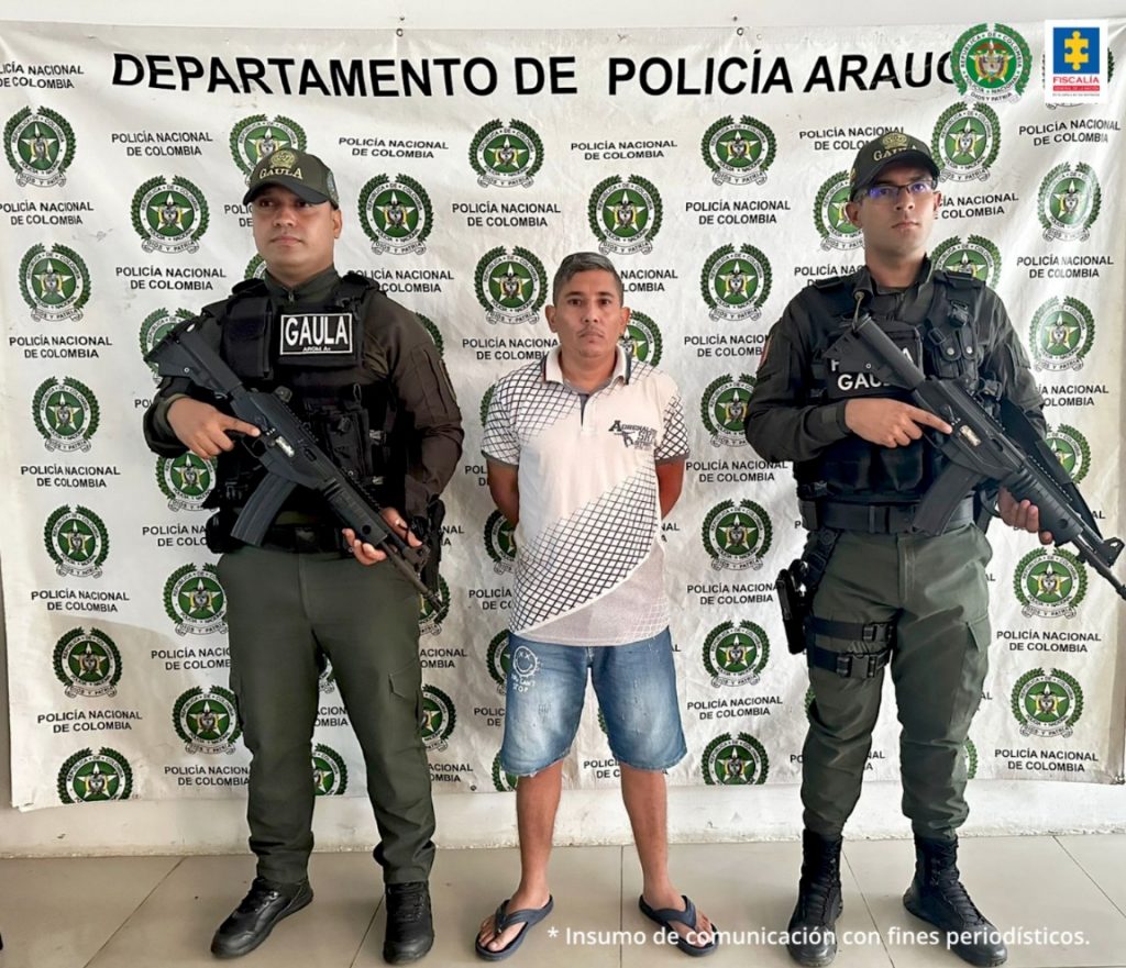 En la imagen se aprecia al capturado junto a dos uniformados de la Policía Nacional. Detrás de ellos el banner que identifica al Departamento de Policía en Arauca