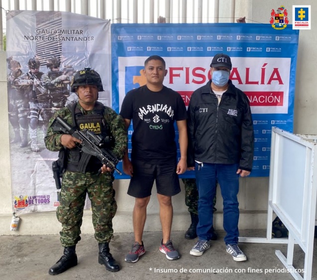 En la imagen se aprecia al capturado junto a un uniformado del Ejército y un investigador del CTI. En la parte posterior se observa los banners que identifican al Ejército Nacional y a la Fiscalía General de la Nación.