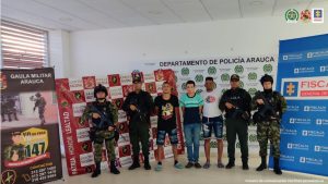En la imagen se observa a los tres capturados junto a un investigador del CTI y uniformados del Gaula Militar y Policía Nacional. En la parte posterior se visualizan los banner que identifican al Gaula Militar Arauca, Ejército Nacional, Departamento de Policía Arauca y a la Fiscalía General de la Nación