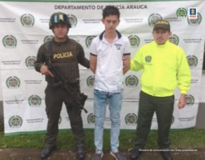 En la imagen se aprecia el capturado junto a dos uniformados de la Policía Nacional. En la parte posterior se observa el banner que identifica al Departamento de Policía Arauca.