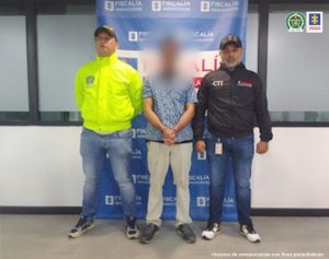 En la fotografía aparece el capturado con el rostro difuminado junto a investigadores de la Sijin y CTI. En la parte posterior se observa el banner que identifica a la Fiscalía General de la Nación