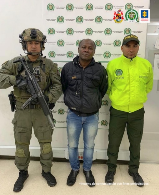En la imagen se aprecia el capturado junto a uniformados de la Policía y Ejército Nacional. En la parte posterior se observa el banner que identifica a la Policía Nacional.