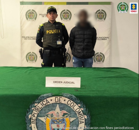 En la imagen aparece el capturado con el rostro difuminado junto a un uniformado de la Policía Nacional. En la parte posterior se observa el banner que identifica a la Policía Nacional.