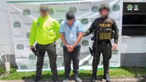 Se observa al capturado junto a dos uniformados de la Policía Nacional. Detrás de ellos el banner que identifica a la Policía Nacional.