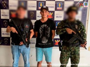 En la imagen se aprecia al capturado junto a un investigador del CTI y a uniformado del Gaula Militar. En la parte posterior se observa un banner con los logos que identifican a la Fiscalía General de la Nación y a las Fuerzas Militares.
