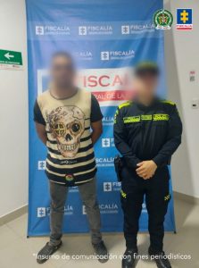 Se observa al capturado junto a uniformado de la Policía Nacional. Detrás se ubica el banner que identifica a la Fiscalía General de la Nación.