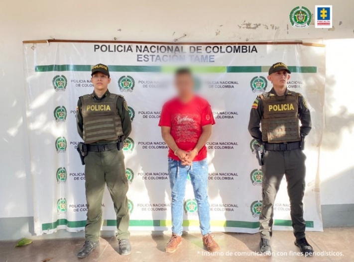 En la imagen se observa al capturado junto a dos uniformados de la Policía Nacional. Detrás de ellos el banner que identifica a la Policía Nacional.