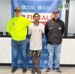 En la imagen se aprecia al capturado junto a integrante de la Sijin y un investigador del CTI. En la parte posterior se observa el banner que identifica a la Fiscalía General de la Nación.