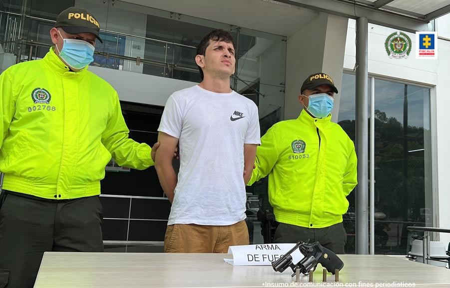 En la imagen se observa al capturado junto a dos uniformados de la Policía Nacional. Al frente de ellos el arma incautada al momento de la captura