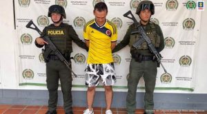 : En la imagen se observa al capturado junto a dos uniformados de la Policía Nacional. Detrás de ellos el banner que identifica al Departamento de Policía de Arauca