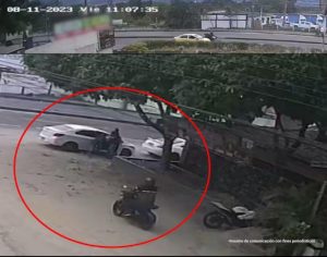 En al imagen se ve a dos hombres abriendo la puertas de un carro blanco y una moto.