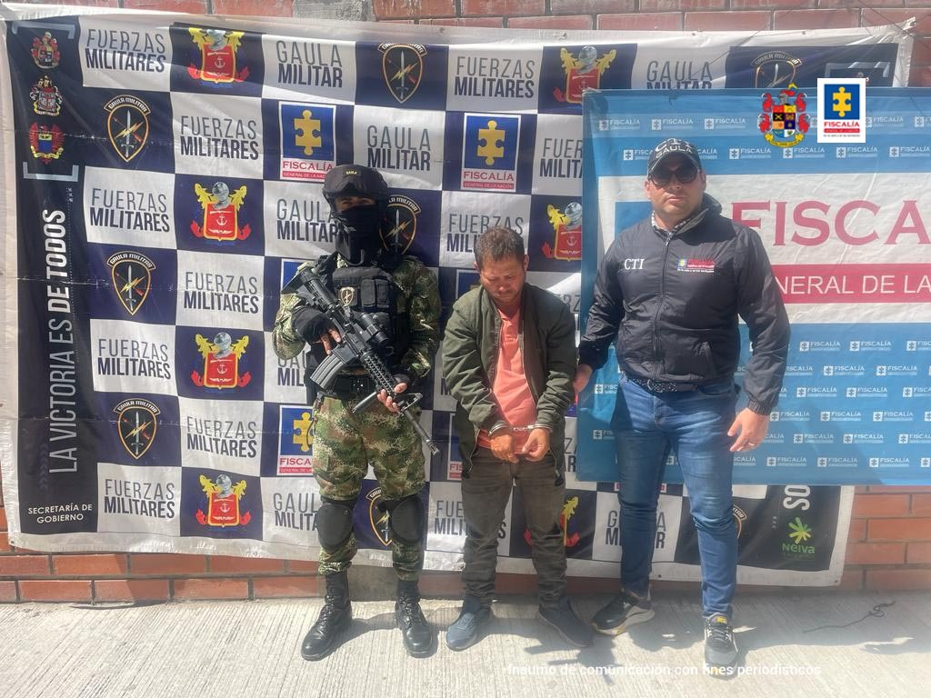 en la imagen se ve una persona detenida bajo custodia de un integrante del Ejército y de un investigador del CTI. Detrás suyo backings institucionales.