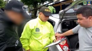 en la imagen se ve una persona detenida a quien le están leyendo sus derechos un uniformado de la Policía Nacional y un investigador del CTI.
