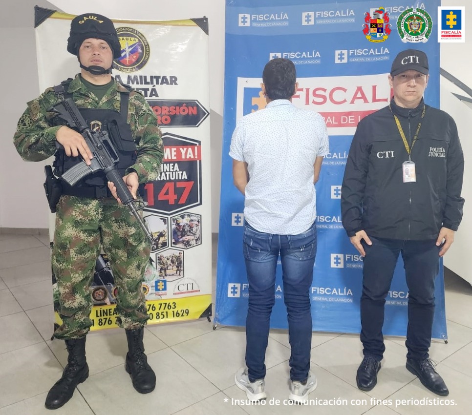 en la imagen se ve un hombre detenido dando la espalda, bajo custodia de un militar y de un investigador del CTI. Detrás suyo dos backings de cada una de las instituciones.