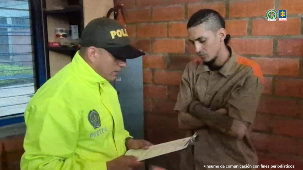 en la imagen se ve un uniformado de la Policía Nacional leyéndole los derechos como capturado a una persona.