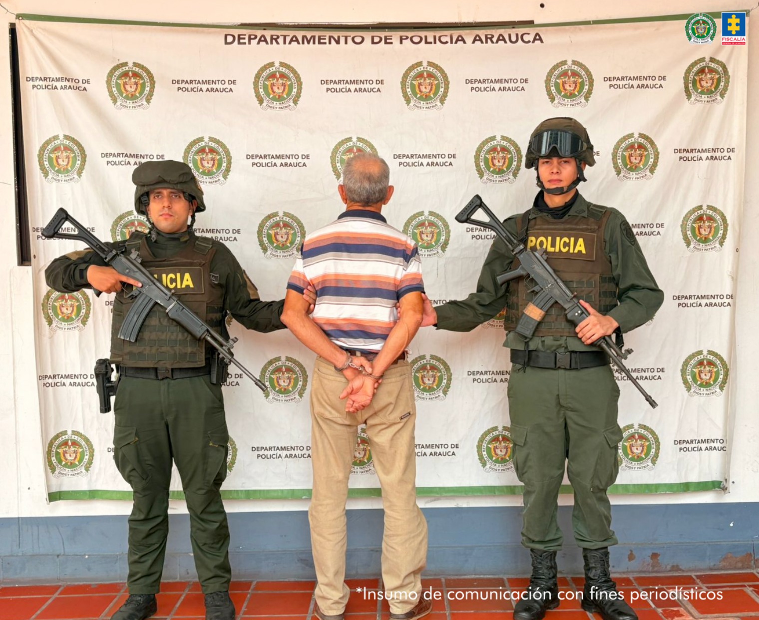 Se observa al capturado de espaldas junto a dos uniformados de la Policía Nacional. Detrás de ellos el banner que identifica a la Policía Nacional.