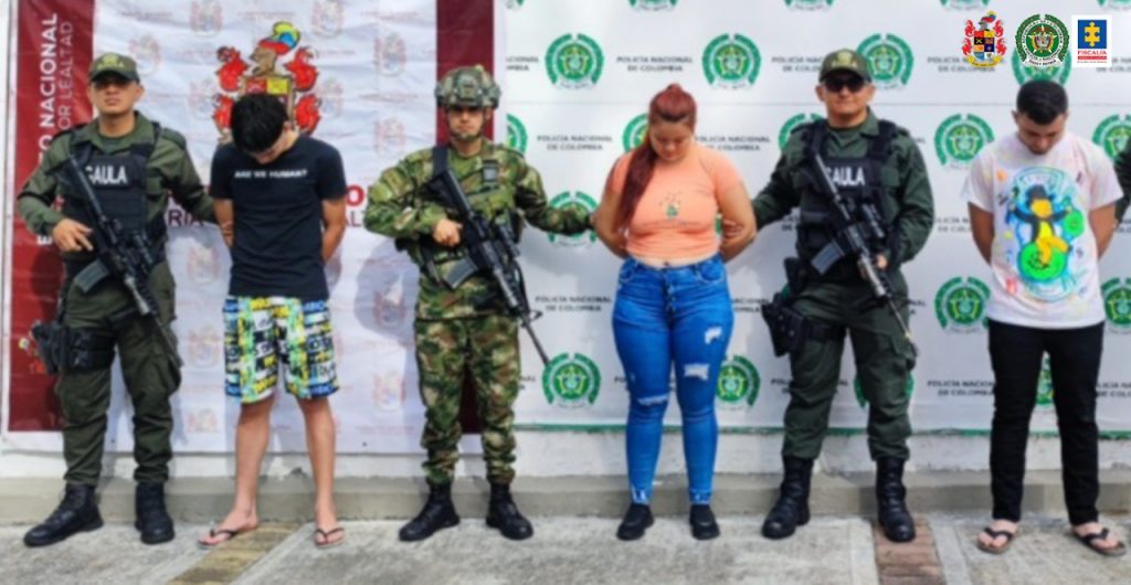 En la imagen se encuentran tres personas detenidas con miembros del CTI, Gaula Militar y Policía Nacional del grupo Gaula. Detrás suyo, pendones alusivos a la Policía Nacional y el Ejército.