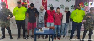 En la imagen dos se ven 5 detenidos acompañados por Ponal y Ejército nacional. Backing del Ejército Nacional y PONAL. En la mesa marihuana y una escopeta.