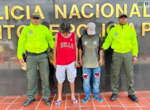 Dos hombres bajo custodia de integrantes de la Policía Nacional.