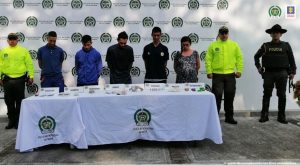 En la imagen se ven cinco personas detenidas bajo custodia de integrantes de la Policía Nacional. Detrás suyo un backing de la institución.