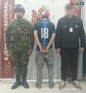En la imagen se ve una persona detenida de espaldas, bajo custodia de un investigador del CTI y un integrante del Ejército.