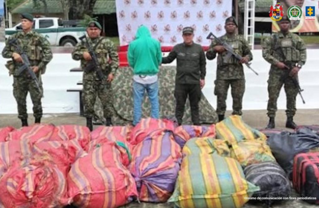 en la imagen se ve un hombre detenido bajo custodia de varios uniformados de la Policía Nacional y el Ejército.