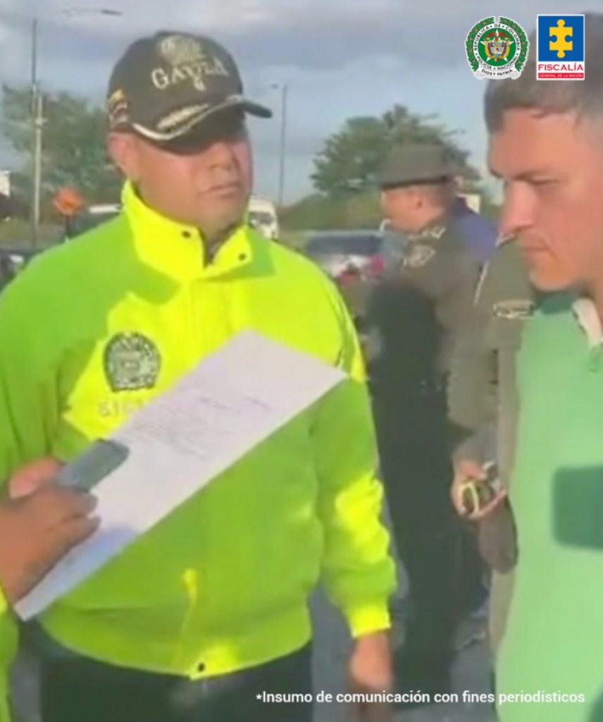 En la foto se aprecia a Harold Andrei Echeverry Orozco, en una vía pública, cuando fue capturado por otros hechos, en Villavicencio (Meta), el 11 de diciembre de 2023. Viste camisa de manga corta verde. Frente a él hay un uniformado de la Policía Nacional.
