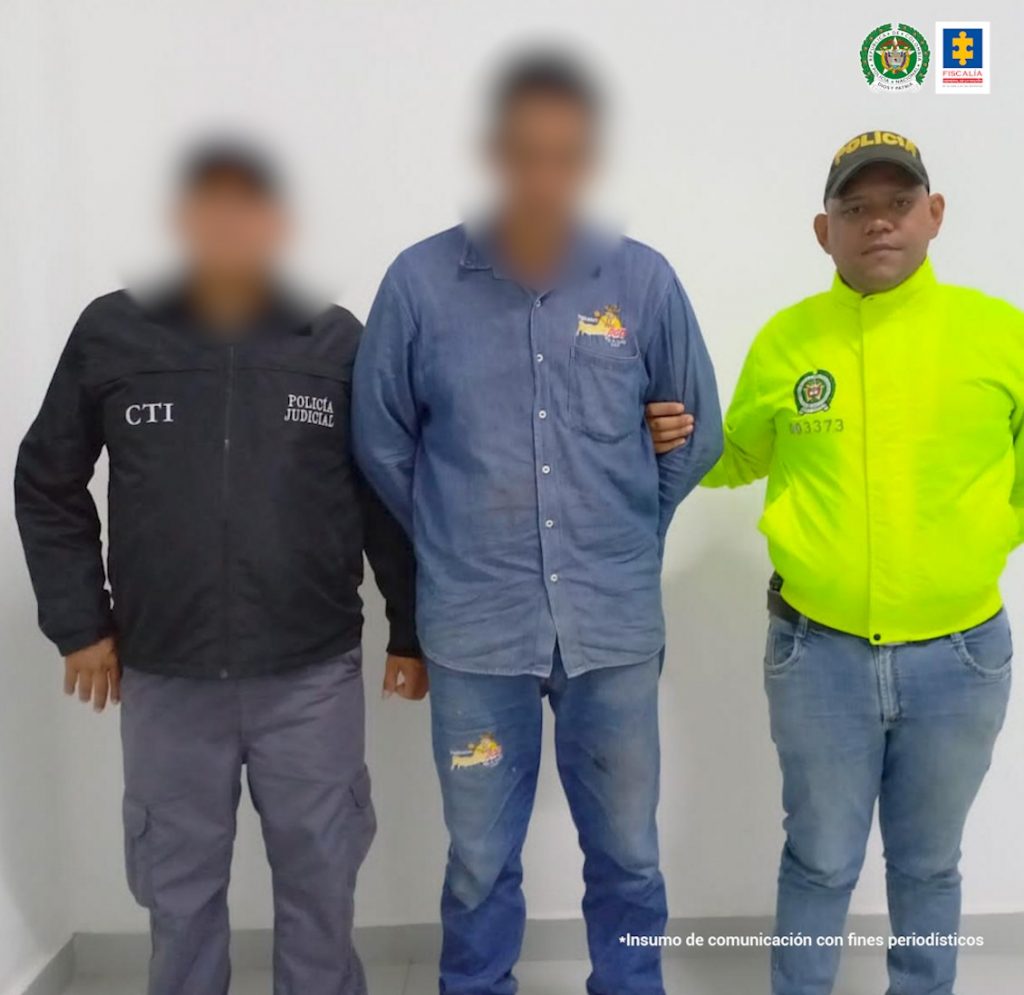 En la imagen se ve una persona capturada entre un funcionario de la Policía y uno de la Fiscalía.