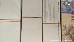 se ven hojas de papel, y bolívares, así como recibos en la imagen.