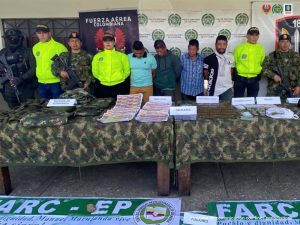 En la imagen se ven cinco personas detenidas bajo custodia de la Policía, Ejército, Fuerza Aérea. Delante suyo una mesa con varios elementos incautados. Detrás, backing alusivos a las instituciones.