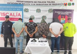 En la imagen se ven cuatro personas detenidas bajo custodia del CTI y la Policía Nacional. Detrás suyo backings institucionales.