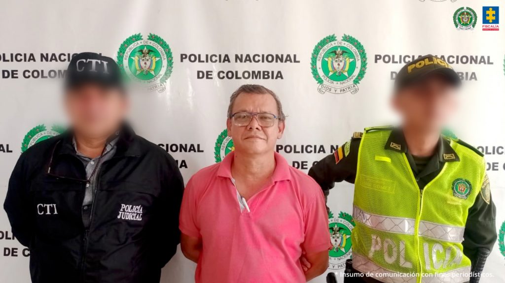 en la imagen se ve un hombre detenido bajo custodia de un uniformado de la Policía Nacional y un investigador del CTI.