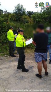 Dos personas de la Policía en un operativo de captura. El capturado está de espaldas, no puede verse su rostro. 