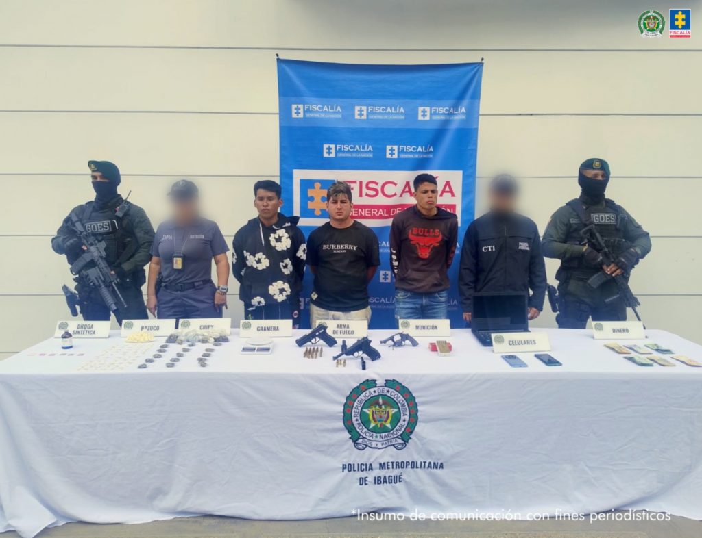 En la imagen cuatro personas detenidas bajo custodia de las autoridades. Detrás suyo un backing institucional. Delante de ellos una mesa con elementos incautados.