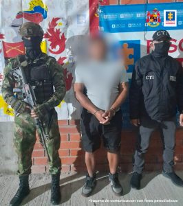  en la imagen se ve una persona detenida bajo custodia de un investigador del CTI y un integrante del Ejército. 