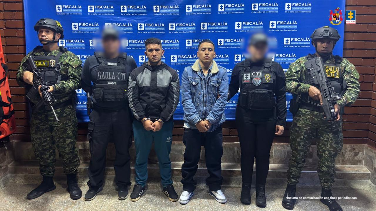 Los capturdos aparecen de pie en el centro de la imagen, con un banner de la Fiscalía de fondo. Aparecen rodeados del CTI y del Gaula del Ejército.