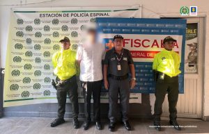 en la imagen se ve una persona detenida bajo custodia de integrantes del CTI y la Policía. Detrás suyo un backing institucional.