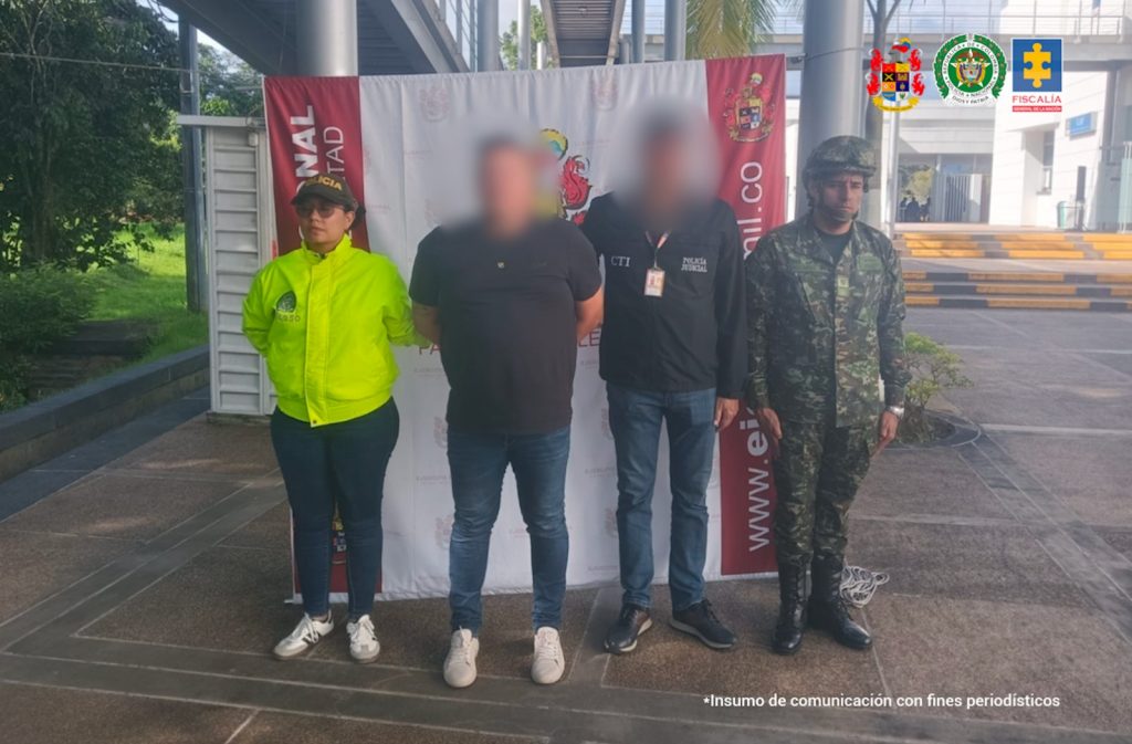 en la imagen se ve un hombre detenido bajo custodia de un investigador del CTI, la Policía y el Ejército. Detrás suyo un backing institucional.
