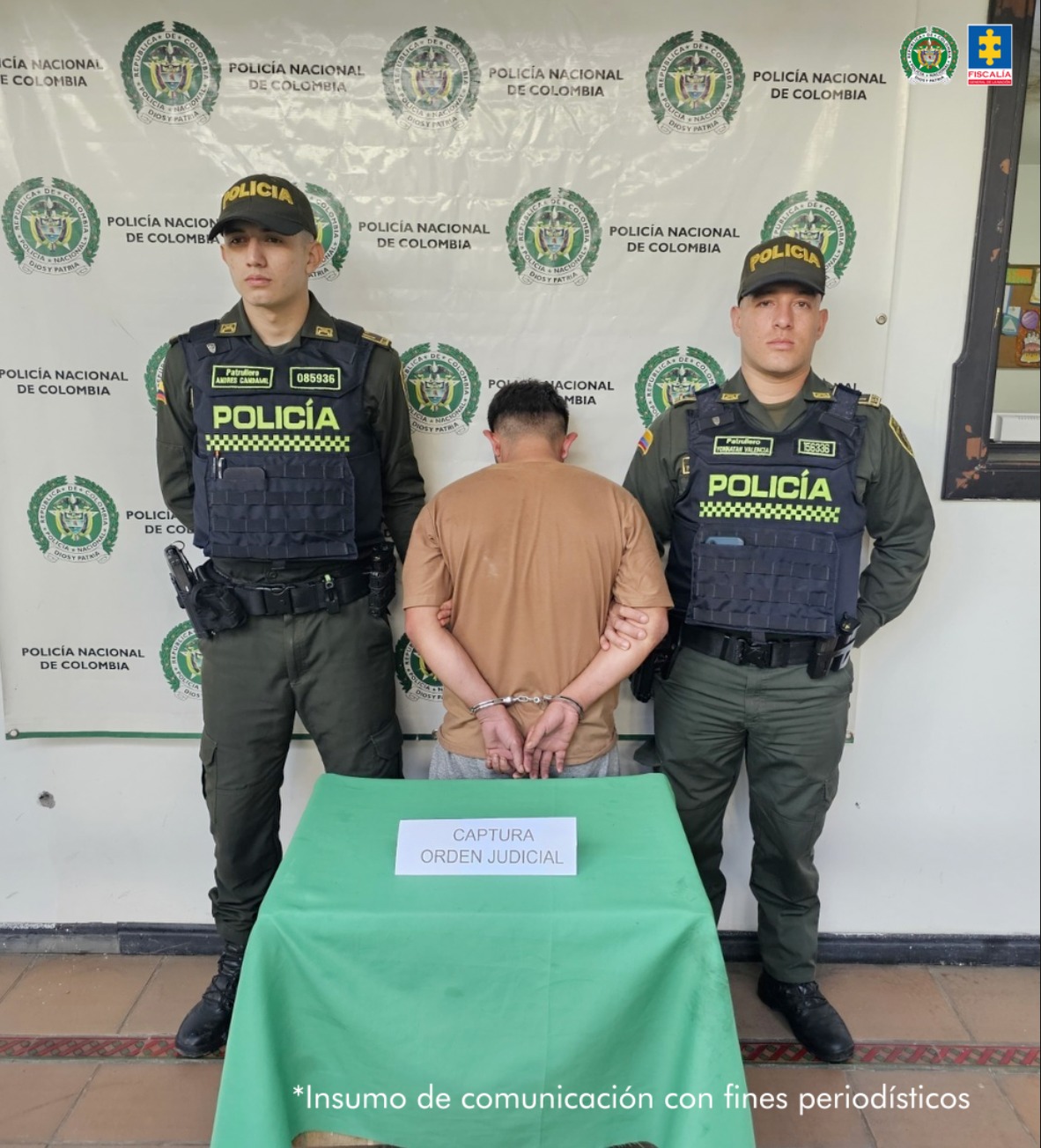 En la imagen se ve una persona detenida de espaldas, bajo custodia de dos integrantes de la Policía Nacional.