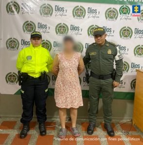 En la fotografía está la procesada con el rostro distorsionado y dos servidores de la Policía Nacional a los lados