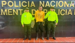 En la imagen se ve una persona detenida en custodia de dos integrantes de la Policia Nacional.