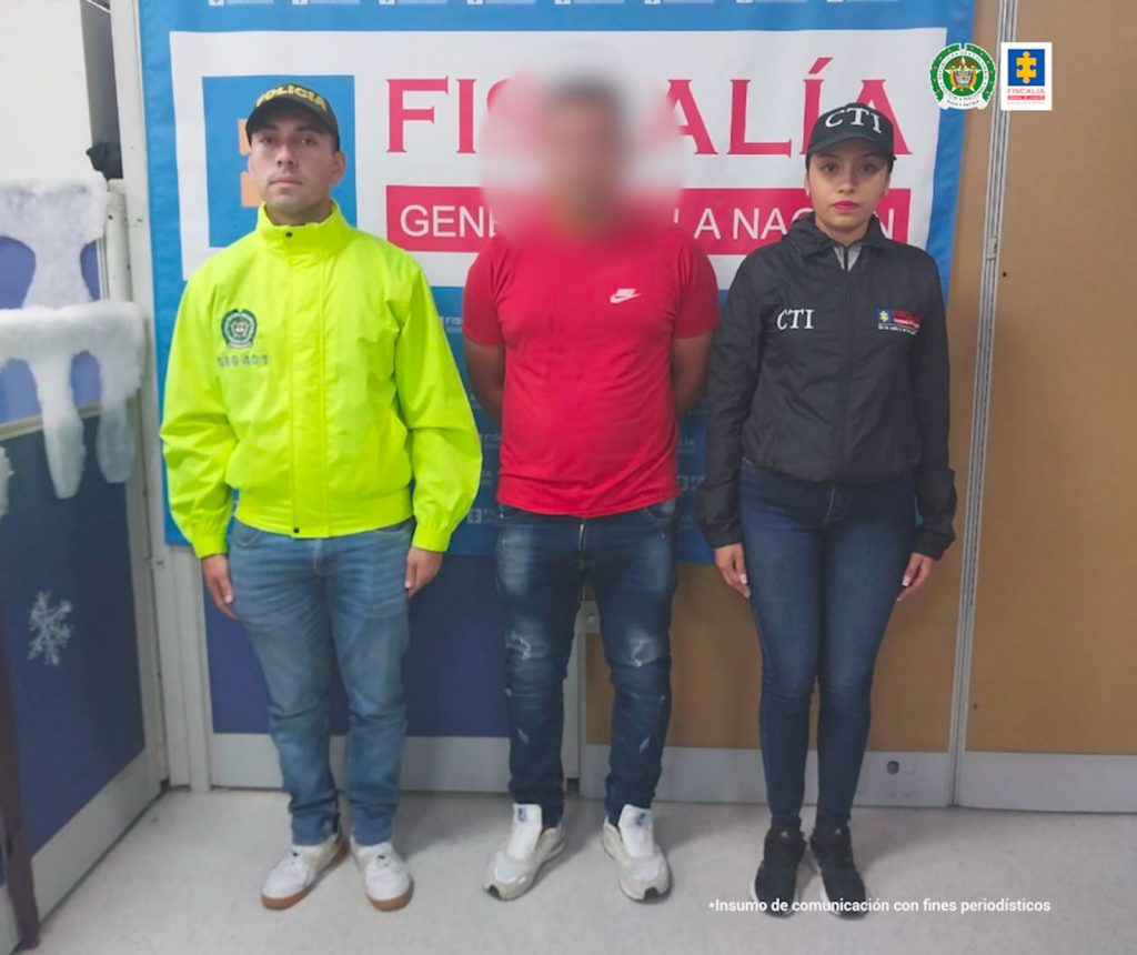 responsable de maltratar a su compañera sentimental en vía pública de IbaguéTEXTO ALTERNATIVO: En la imagen está el procesado con un servidor del CTI y otro de la Policía Nacional y un pendón de la Fiscalía en la parte de atrás.