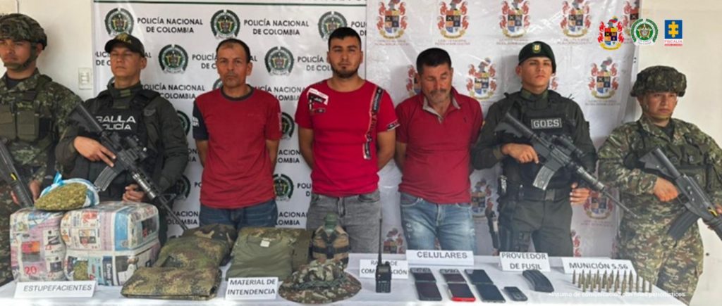 En la imagen se ven varias personas detenidas bajo custodia de la Policía Nacional y el Ejército. DEtrás suyo un backing institucional. Delante de ellos elementos incautados.
