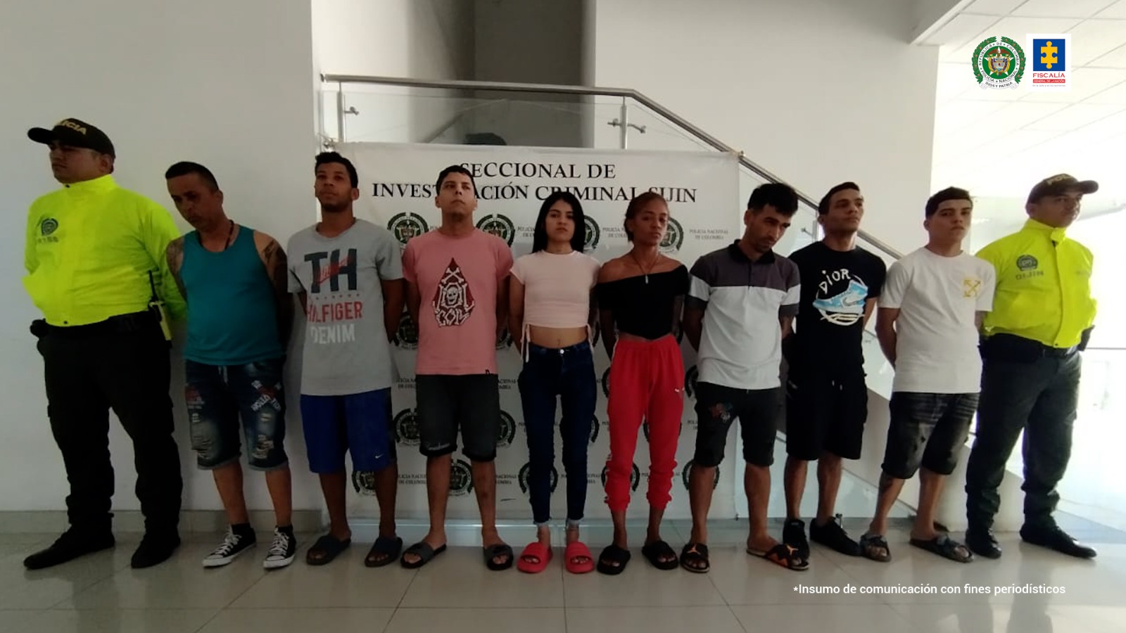 En la imagen aparecen 8 personas capturadas, en medio de dos agentes de la Policía.