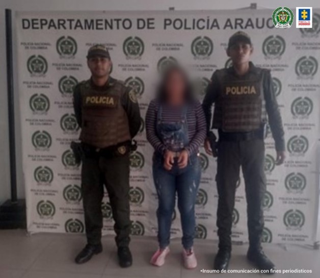 En la imagen se aprecia a la mujer capturada junto a dos uniformados de la Policía Nacional, detrás de ellos un banner de la Policía de Arauca.