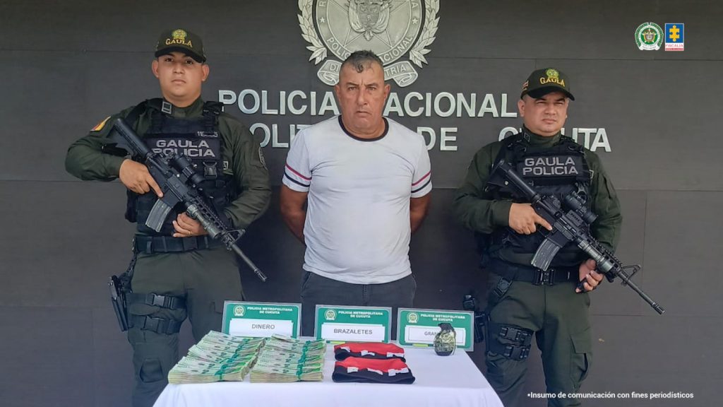 Se observa al capturado junto a dos uniformados del Gaula de la Policía Nacional. Frente a ellos el dinero recuperado producto de la extorsión.