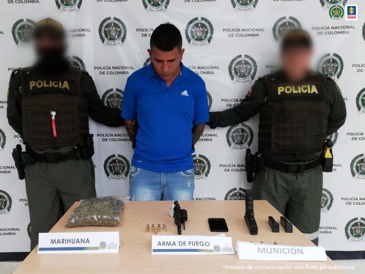 En la fotografía aparece un capturado, junto a personal de Policía Nacional y Fiscalía General de la Nación. En la parte posterior de la imagen se ven banners de Policía Nacional y la Fiscalía General de la Nación.