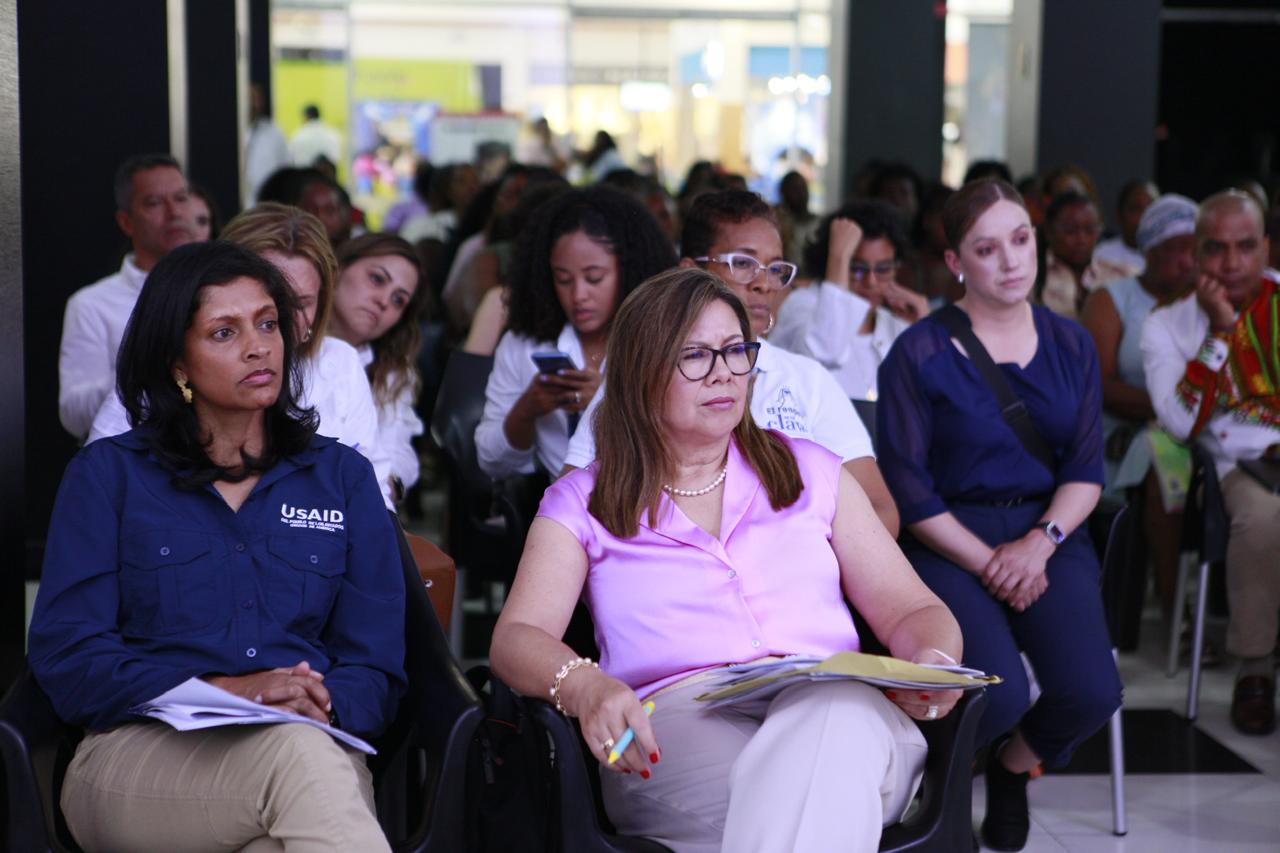 En la imagen se ve la fiscal Luz Adriana Camargo al lado de la directora de USAID de Misión Colombia, Anu Rajaraman. Al fondo pueden verse más personas, entre funcionarios de la Fiscalía y ciudadanos. 