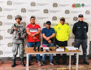 En la imagen se ven dos personas capturadas y bajo la custodia de un representante de la Fiscalía, la Policía Nacional y el Ejército Nacional.