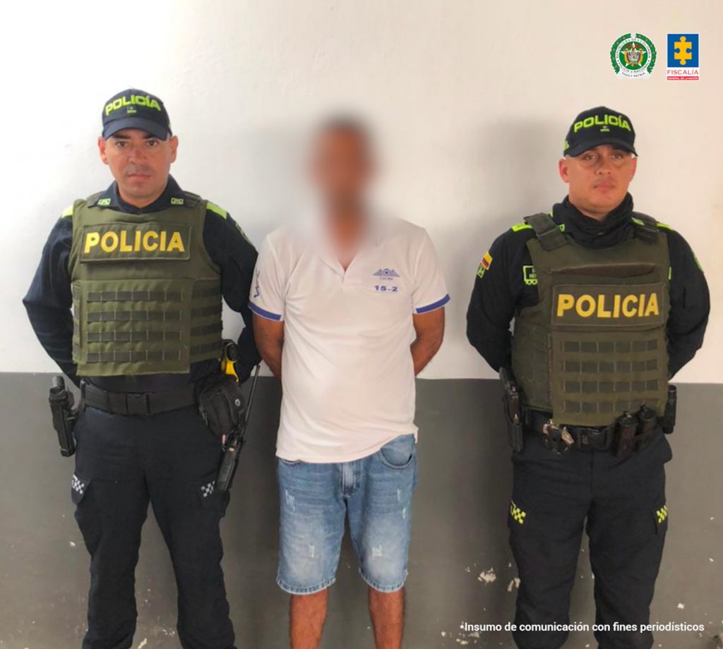En la imagen aparece una persona de jean y camiseta blanca, entre dos uniformados de la Policía. 